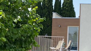 Un edificio moderno con balcón, pared de piedra y puerta de cristal.