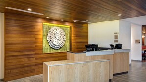 Zona de recepci ón con mostrador de madera, un elemento decorativo en la pared y un mostrador con un teléfono y una mesita.