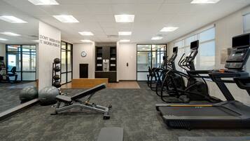 A gym with treadmills, elliptical machines, and free weights.