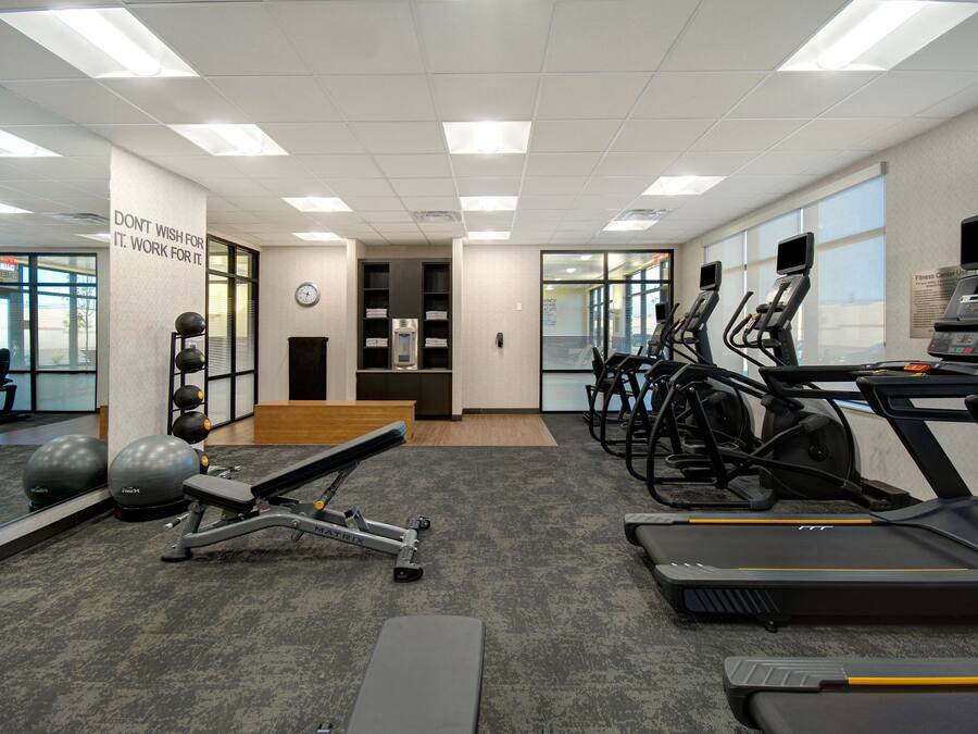 A gym with treadmills, elliptical machines, and free weights.
