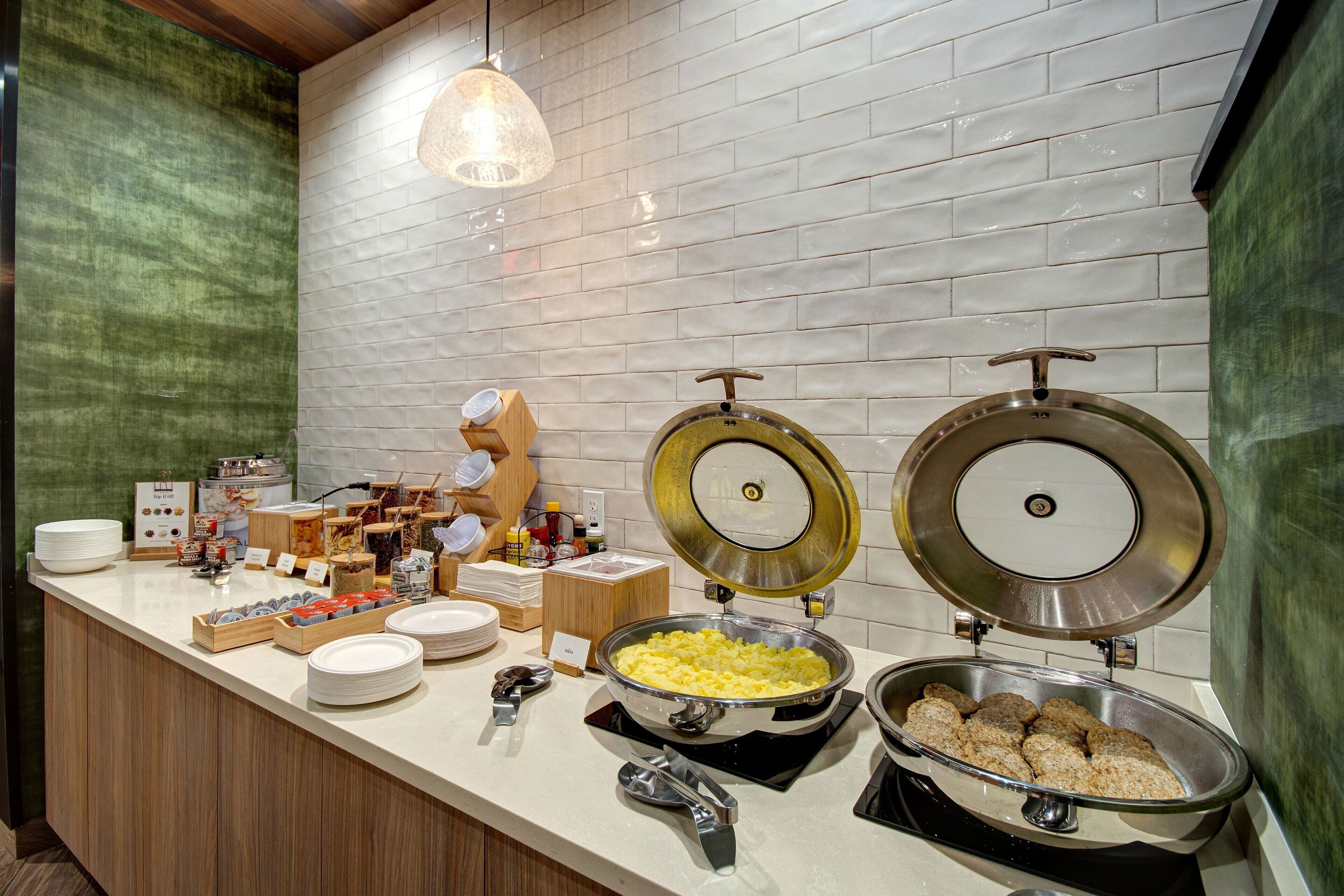 A buffet setup with various food items, including a large pot of scrambled eggs, a bowl of meatballs, and a variety of condiments and dishes.