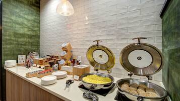 A buffet setup with various food items, including a large pot of scrambled eggs, a bowl of meatballs, and a variety of condiments and dishes.
