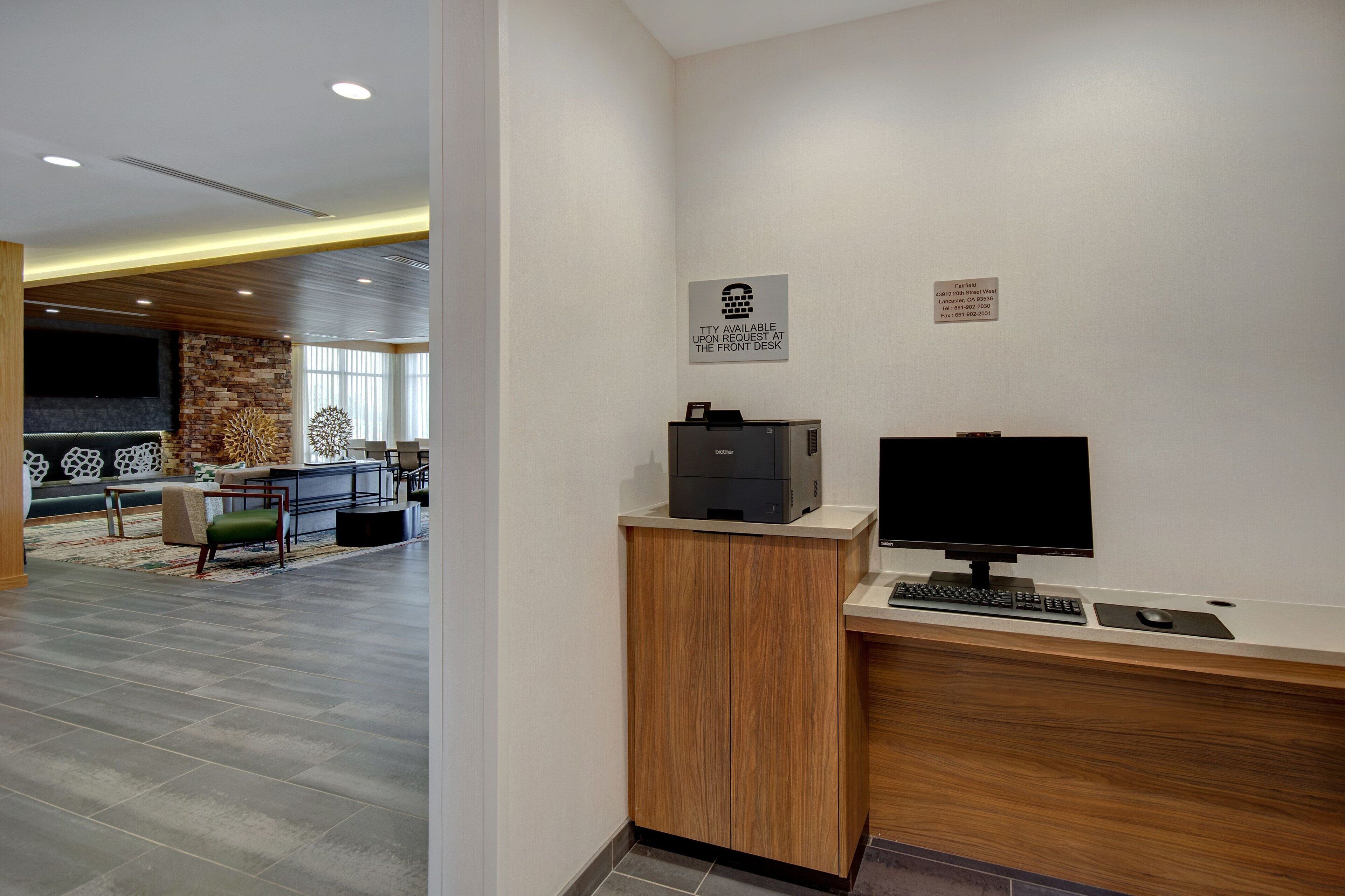A reception area with a wooden desk, a computer, and a flat-screen TV. There is a sign indicating the availability of a private room upon request.