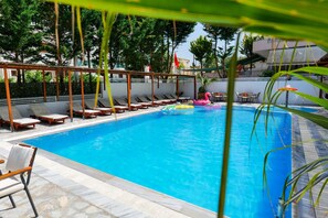 A swimming pool with lounge chairs and a pink flamingo float. - 6 Milje Hotel (Ksamil)