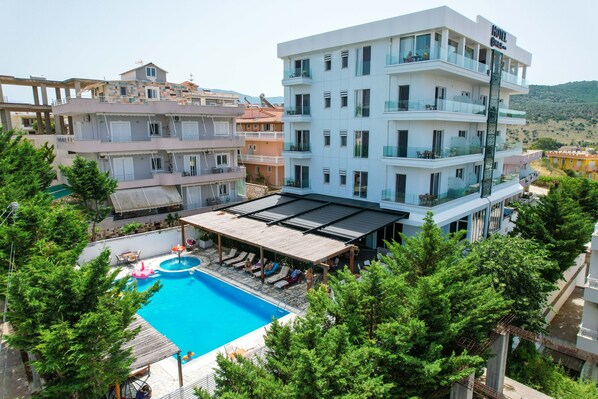 A hotel with a rooftop pool, multiple balconies, and a view of the surrounding area. - 6 Milje Hotel (Ksamil)