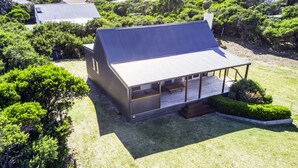 A modern house with a large porch and a covered outdoor seating area.