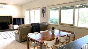 A living room with a sofa, a TV, a fireplace, and a dining area with a table and chairs.