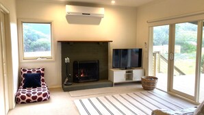A living room with a fireplace, a television, and a sliding glass door to the outdoors.
