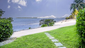 A beach with a clear sky, palm trees, and a pathway leading to the water. - Penthouse on the Beach! Beautiful Sunset Views! (Fort Myers)