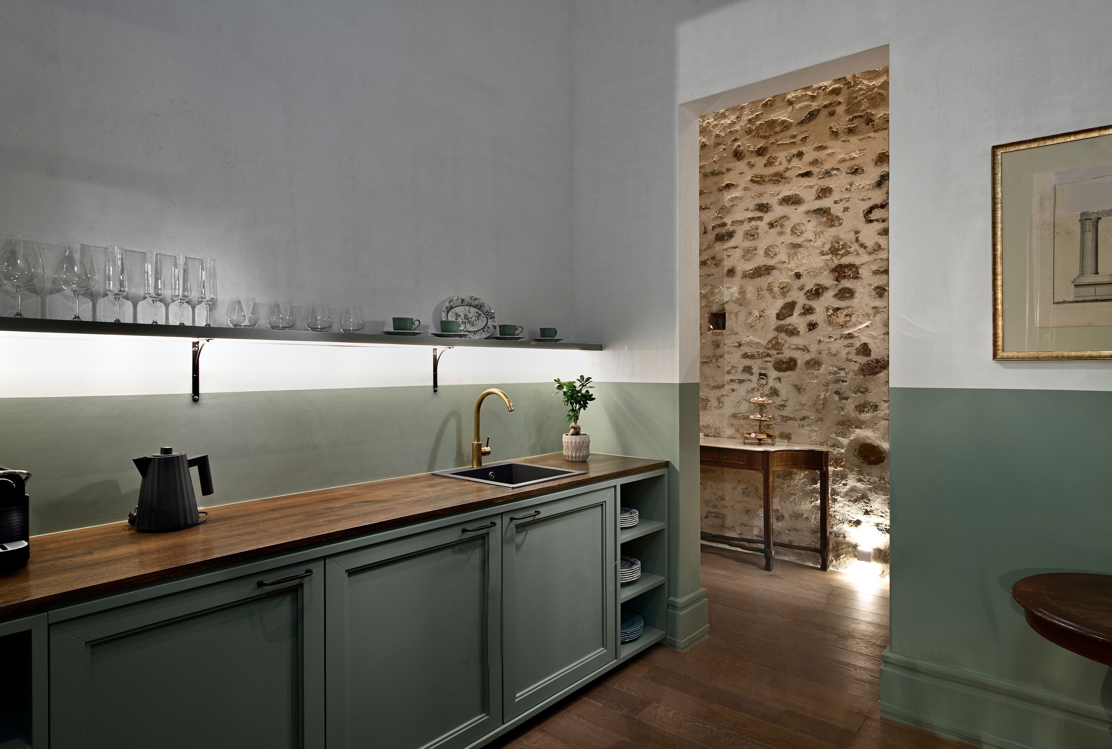 Une cuisine avec un plan de travail en bois, un évier et un mur en pierre.