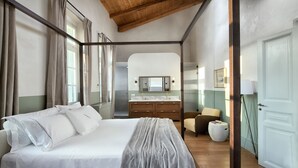 Een slaapkamer met een hemelbed, een dressoir, een stoel en een deur.