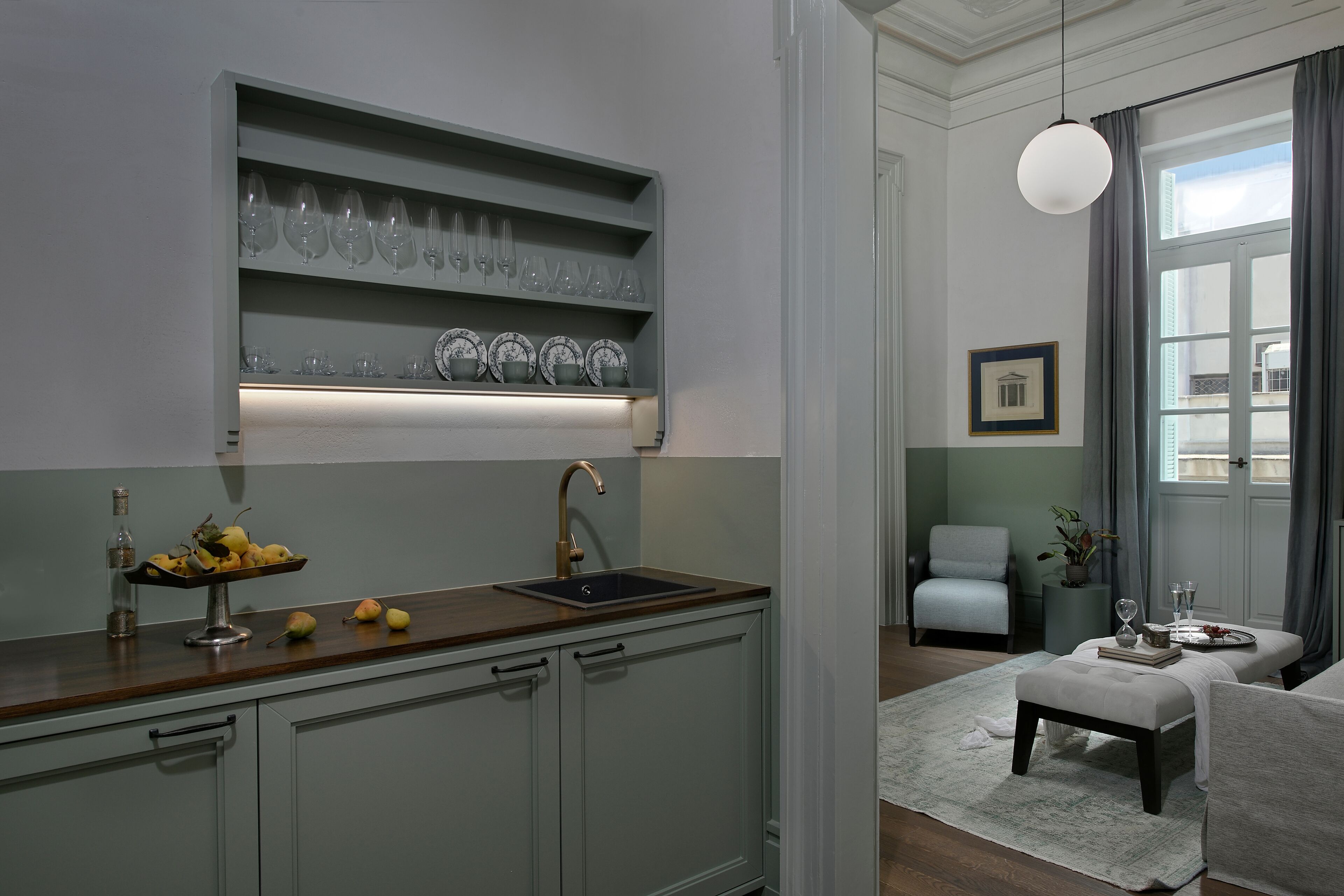 A modern kitchen with a built-in sink, a fruit bowl, and a shelf with glassware.