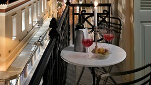 Een balkon met een tafel voor twee, een kaars en twee glazen rode wijn.
