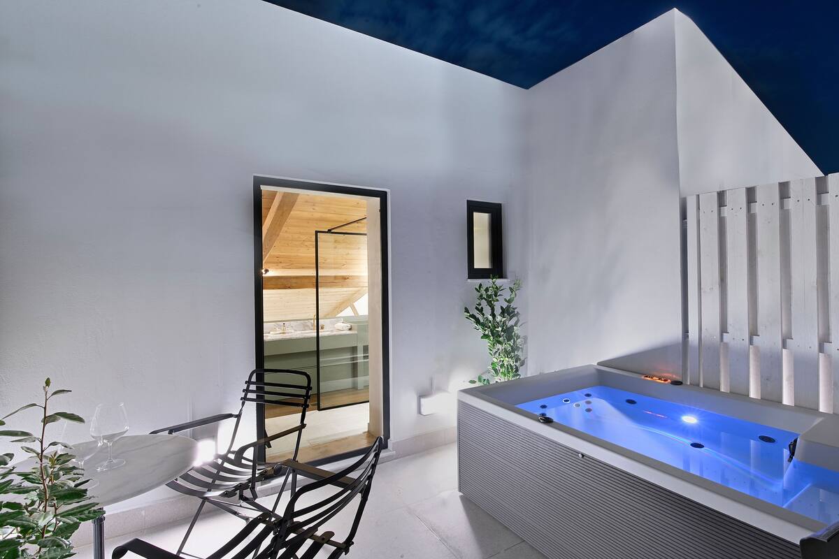 Une salle de bain moderne avec une douche à parois de verre, une baignoire sur pieds dotée d’un éclairage bleu et un plafond en bois.