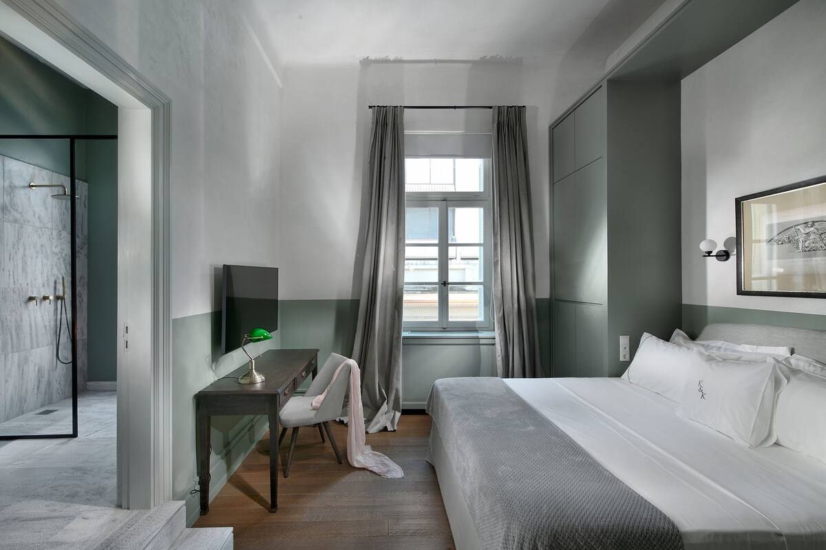 Une chambre d’hôtel moderne équipée d’un lit, d’un bureau avec une chaise, d’une télévision et d’un espace douche.