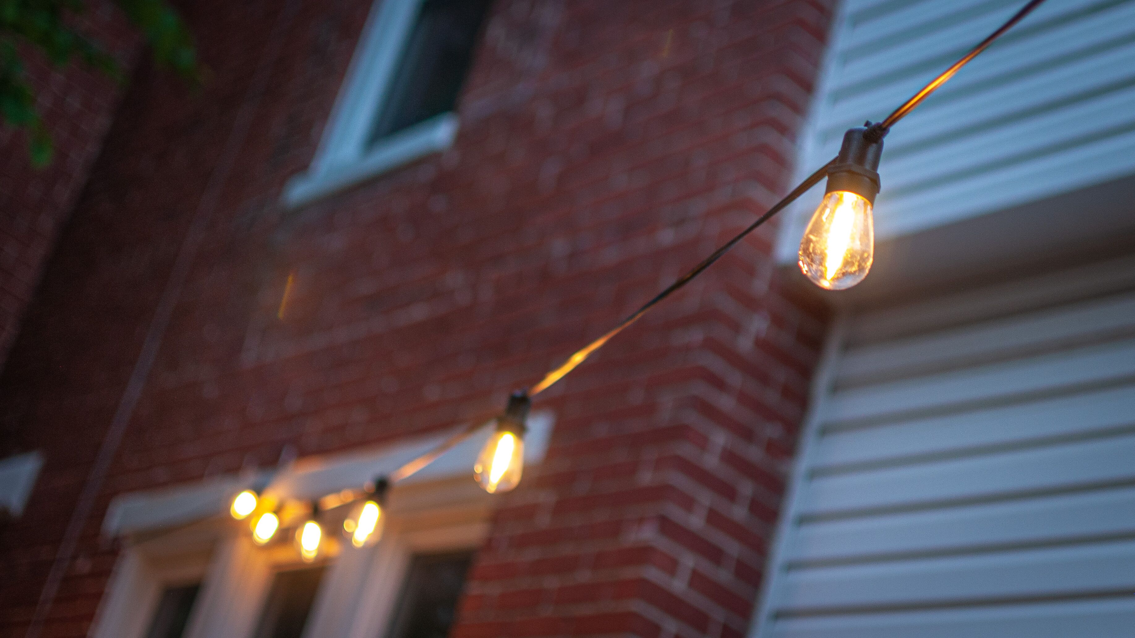 Une guirlande d’ampoules à filament apparentes, fixée à un mur de briques.