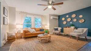 A cozy living room with a brown leather sofa, a round coffee table, and a blue accent wall with woven wall art. - Gorgeous apt, pets, hot tub & fire pit, walk --> DT Frederick (Frederick)