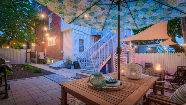 A patio area with a wooden table, chairs, a decorative vase, and a fire pit. - Gorgeous apt, pets, hot tub & fire pit, walk --> DT Frederick (Frederick)