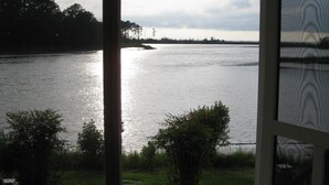 Vista desde un porche cubierto, con vista a un lago, árboles y un muelle a lo lejos.