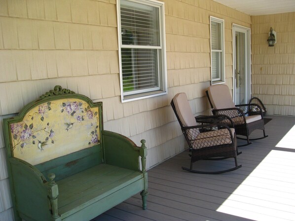 A porch with a green bench and two rocking chairs, a wall-mounted light fixture, and a window with blinds. - 10 Acre 3 BR Waterfront Retreat on Thicket Creek has dock & neighborhood beach
(Onancock)