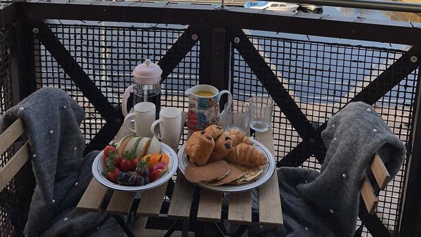 A balcony with a table set for breakfast overlooking a marina with numerous boats.