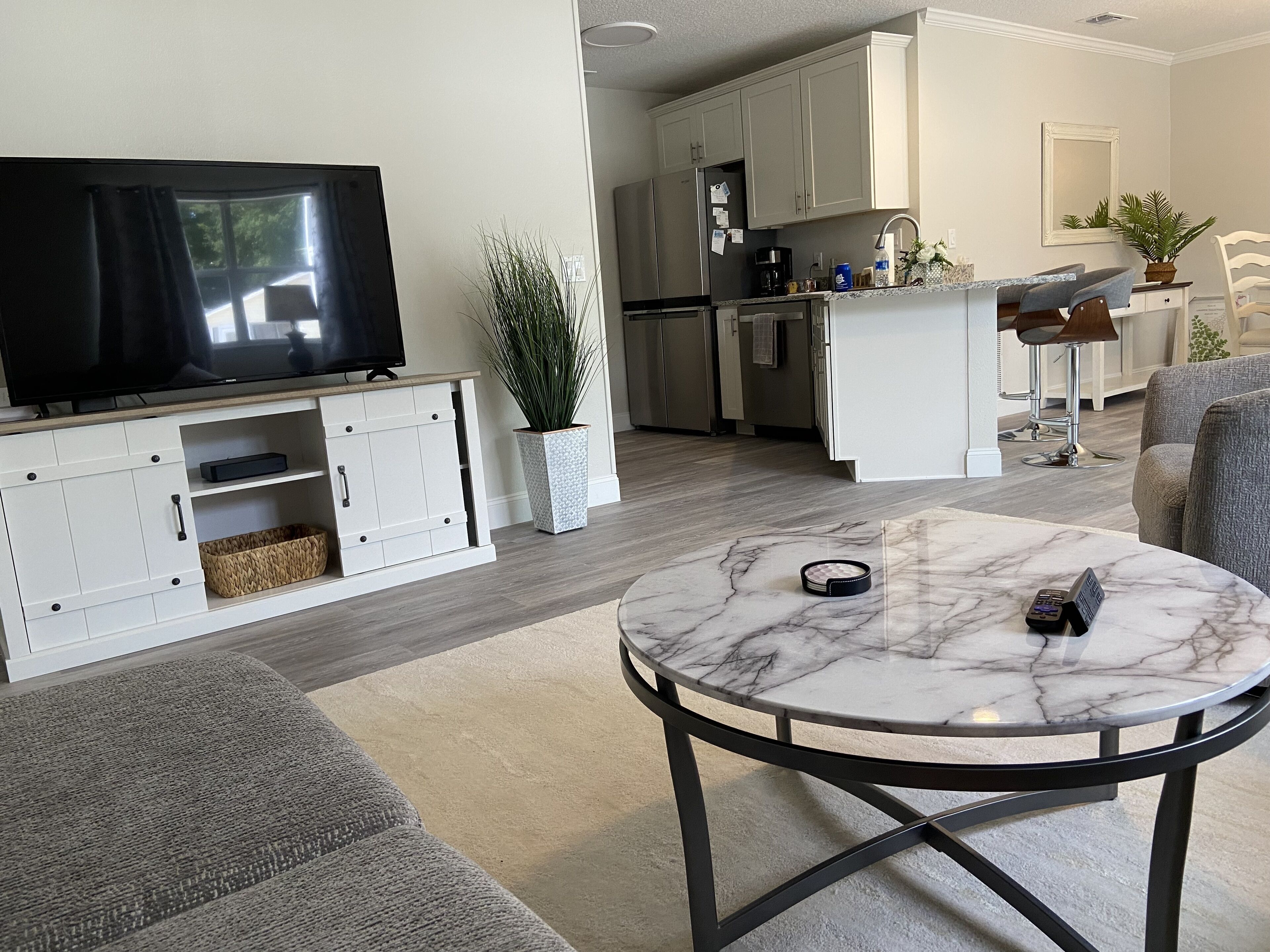 A modern living room with a marble coffee table, a flat-screen TV, and a grey sofa.