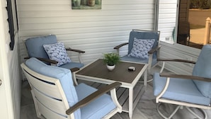 Un patio con due poltrone blu imbottite, un tavolino e una pianta in vaso.