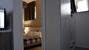 A bedroom with a bed, a bedside table, a lamp, and a wardrobe. - Villa 18 - One-Bedroom House (Matera)