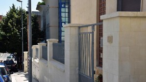 A residential building with a gated entrance, numbered 18, and a parked car on the street. - Villa 18 - One-Bedroom House (Matera)