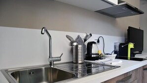 A modern kitchen with stainless steel sinks, a kettle, and a coffee maker. - Villa 18 - One-Bedroom House (Matera)