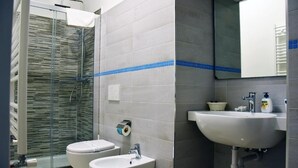 A bathroom with two toilets, a sink, and a shower. - Villa 18 - One-Bedroom House (Matera)
