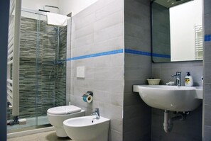 A bathroom with two toilets, a sink, and a shower. - Villa 18 - One-Bedroom House (Matera)