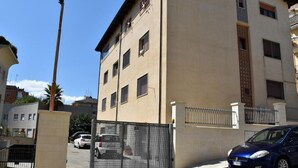 A multi-story building with a beige facade, a gated entrance, and a parked car. - Villa 18 - One-Bedroom House (Matera)