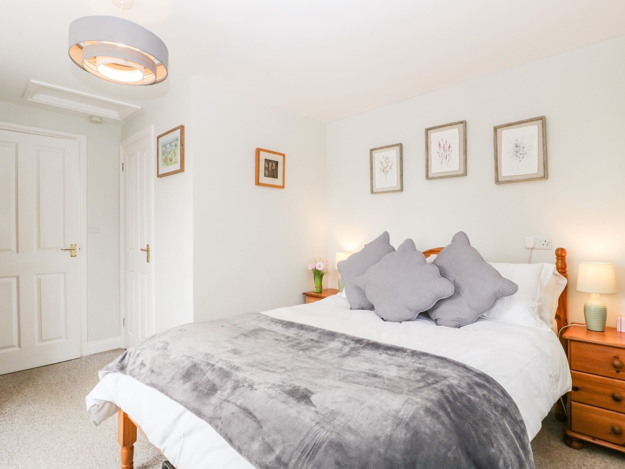 Une chambre à coucher avec un lit, des tables de chevet et des tableaux encadrés accrochés au mur.