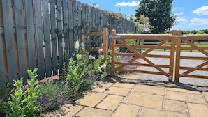 A wooden gate leading to a paved area with a garden. - Thornhills Cottage (Bridgwater)