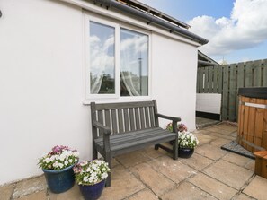A patio with a bench, two flower pots, and a wooden fence. - Thornhills Cottage (Bridgwater)
