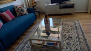 A living room with a blue sofa, a coffee table with books, and a television in the background. - La Goelette 4 (Toulon)