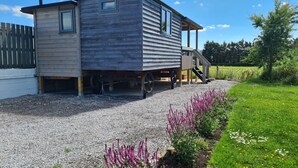 Ein Holzhaus mit gewölbtem Dach, einer Veranda und einer Zuwegung mit Kies.