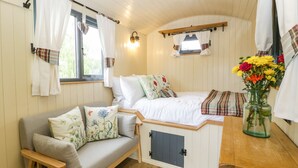 Ein gemütliches Zimmer mit Bett, Sofa, kleinem Tisch und einem Fenster mit Vorhängen.