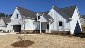 A two-story house with a garage, a small porch, and a tree in the front yard.