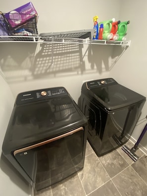 Convenient laundry facilities feature two front-loading washing machines and a storage shelf for cleaning supplies.