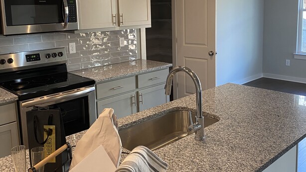 A modern kitchen with stainless steel appliances, granite countertops, and pendant lighting.