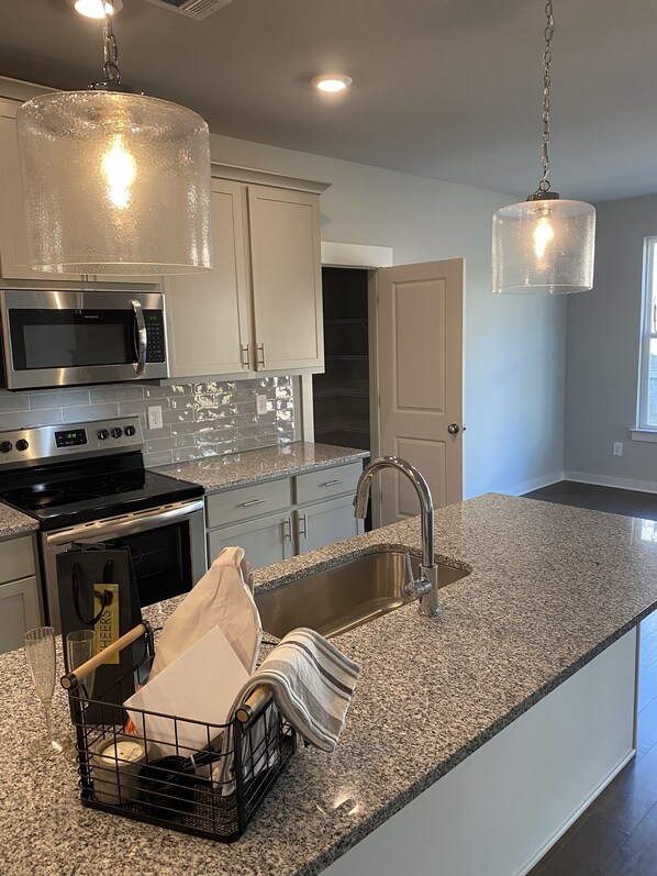 Modern kitchen with stainless steel appliances, granite countertop, and pendant lighting.