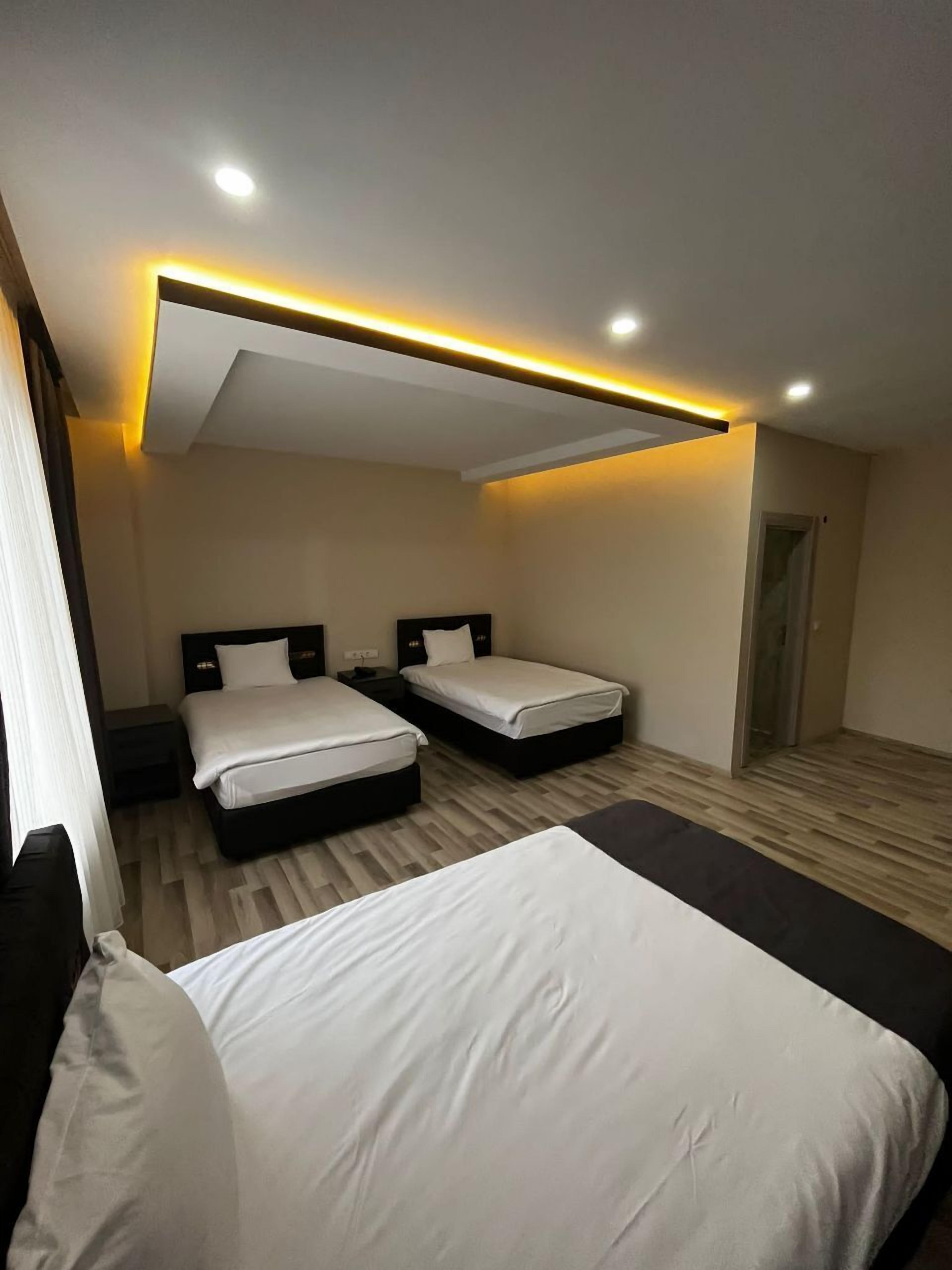 Quarto de hotel com duas camas, uma janela grande e um lustre.