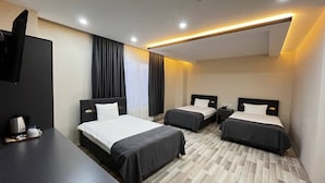 A hotel room with two single beds, a flat-screen TV, a desk with a coffee maker, and a wooden floor. - Atlihan Plus Hotel (Dogubayazit)