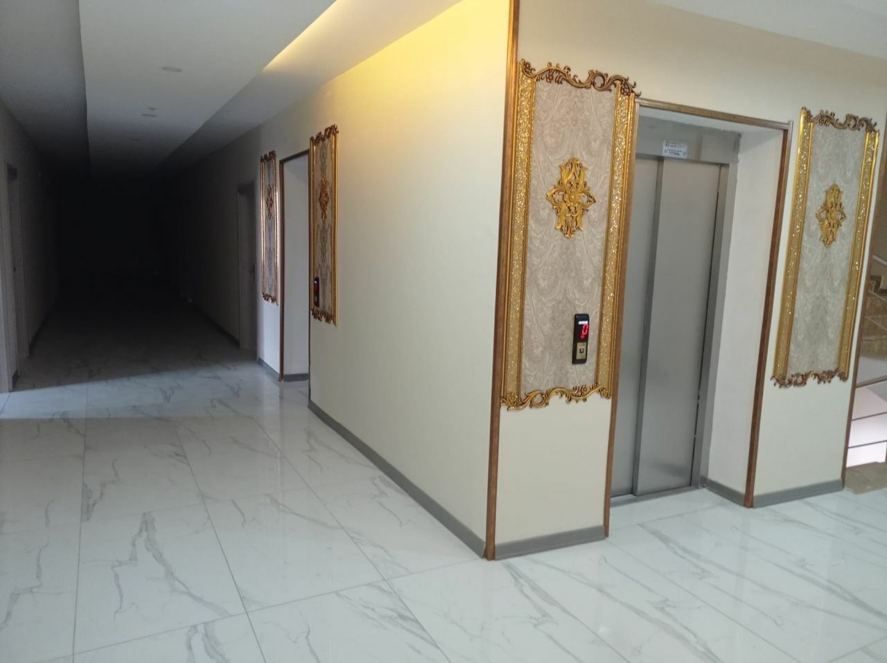 A hallway with marble flooring and ornate wall panels.