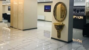 A modern hotel lobby with a marble floor, a reception desk, and a wall-mounted mirror. - Atlihan Plus Hotel (Dogubayazit)