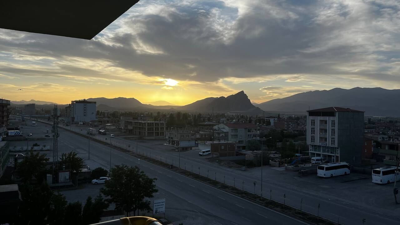 A cityscape with a road, buildings, and mountains in the background.