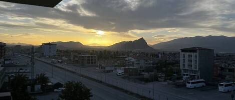 A cityscape with a road, buildings, and mountains in the background.
