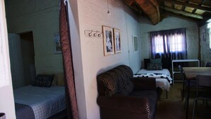 A room with two beds, a sofa, a table, and a window with curtains. - Perdehoek Venue (Lichtenburg)